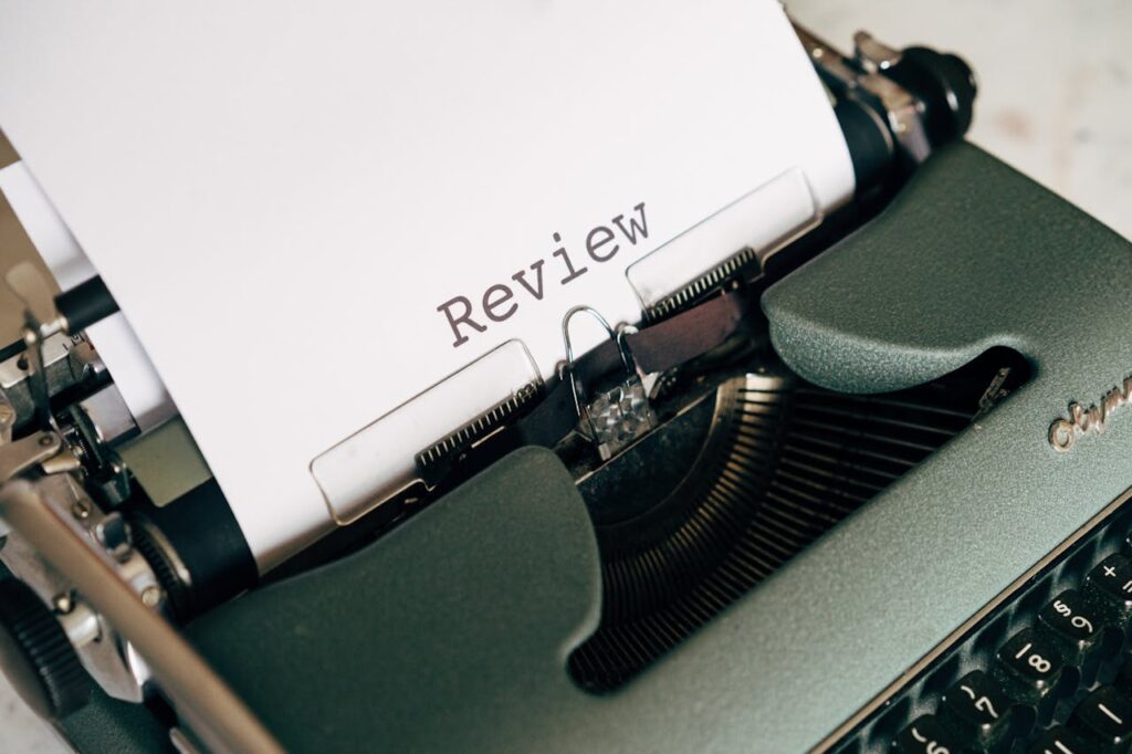 Close-up of an antique typewriter printing the word 'Review' on white paper.